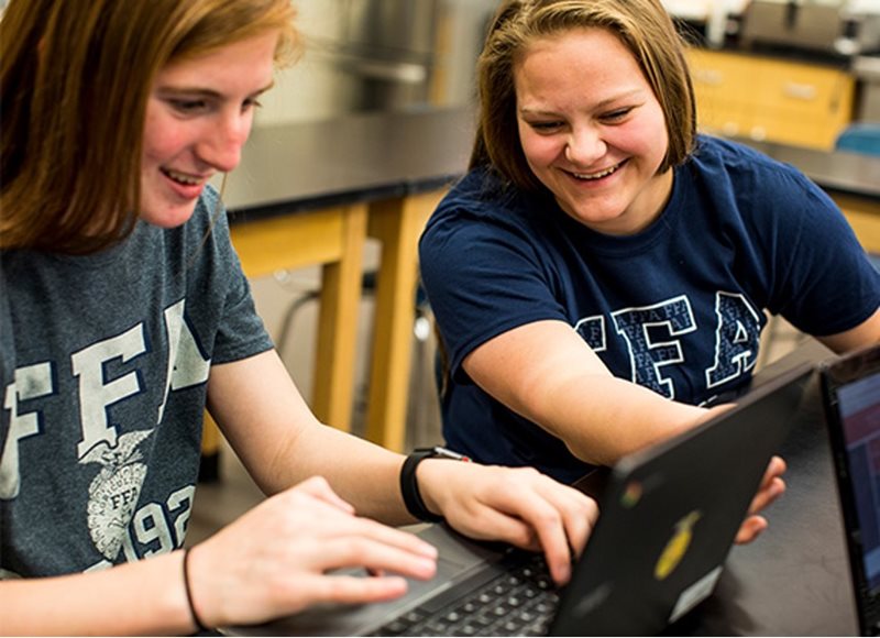 Two FFA members sitting together in front of a computer